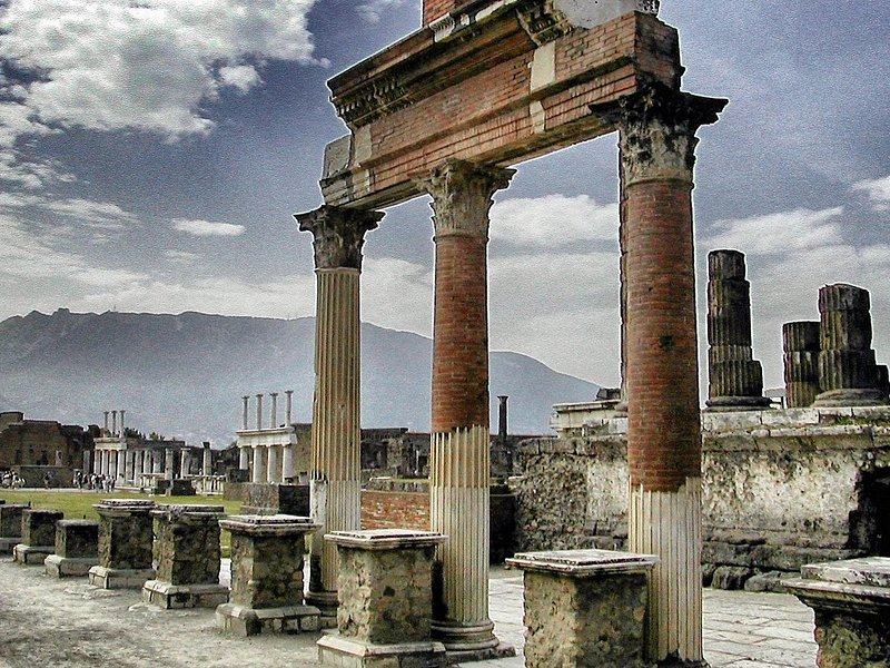 A standing arch and the columns beside it at Pompeii under a heavy sky