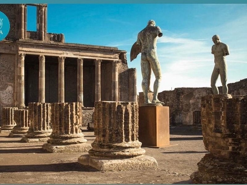 Two modern bronze figures standing among the columns at Pompeii