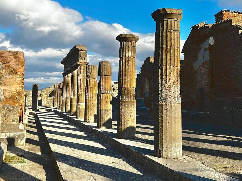 A line of columns at Pompeii throwing long shadows across the paving