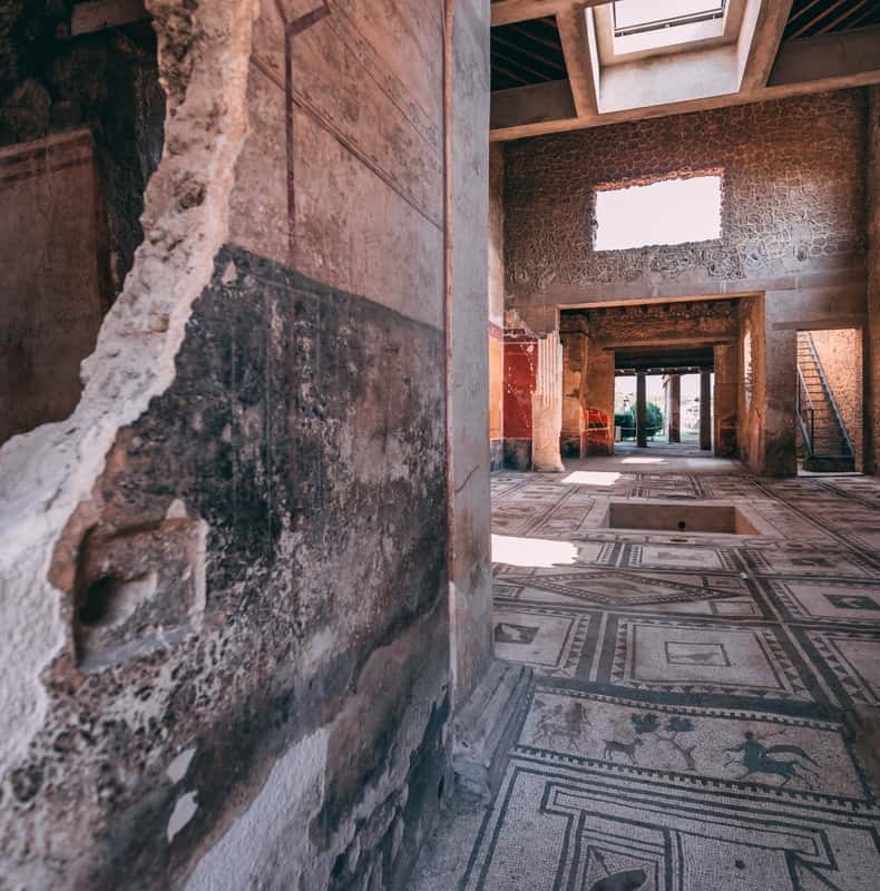 A painted room at Pompeii seen across a mosaic threshold