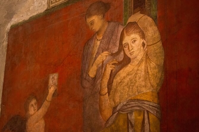 A fresco of two figures on a deep red ground on a house wall at Pompeii